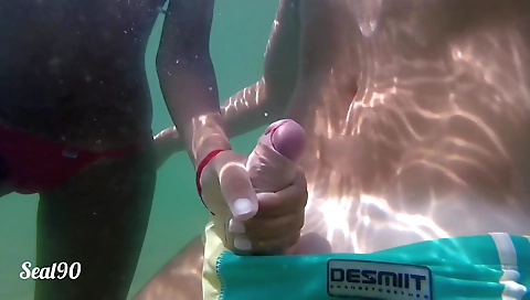 Amateur brunette takes a handjob underwater on the beach